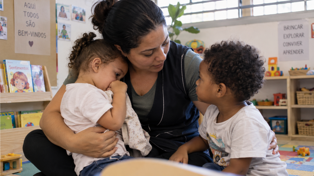 Professora acolhe duas crianças pequenas após uma situação de conflito em um CEI.